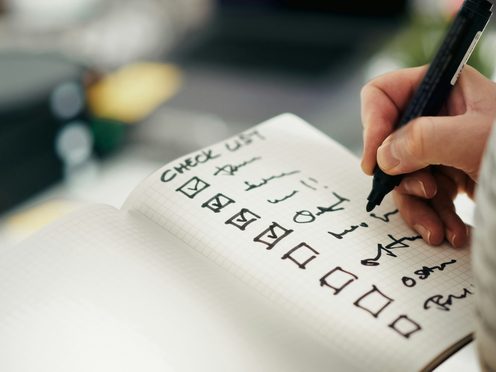 A hand ticking off a handwritten checklist