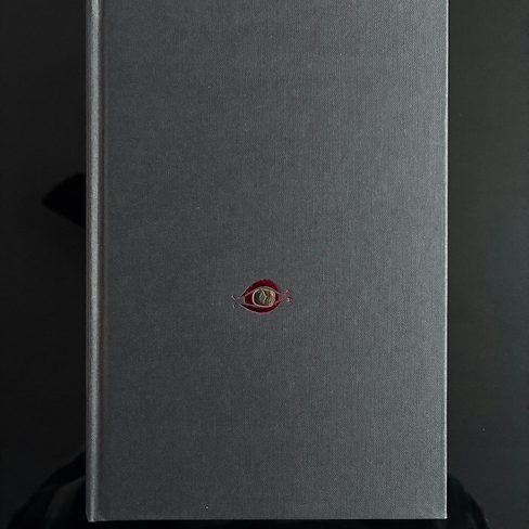 A plain gray hardcover with a small round emblem
