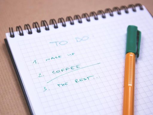 A handwritten to-do list on a spiral notepad with a pen
