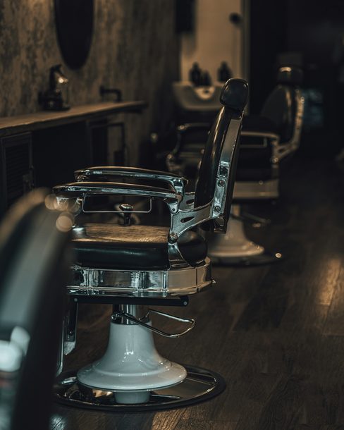 An empty black leather barber chair in a dim shop