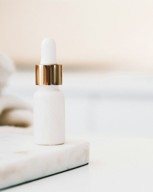 A white dropper bottle on a marble surface