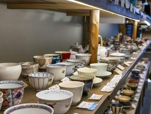 Rows of ceramic bowls and cups on a wooden shelf