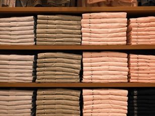 Folded shirts stacked in size order on a wooden shelf