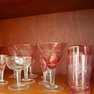 Etched pink and clear glassware on a wooden shelf
