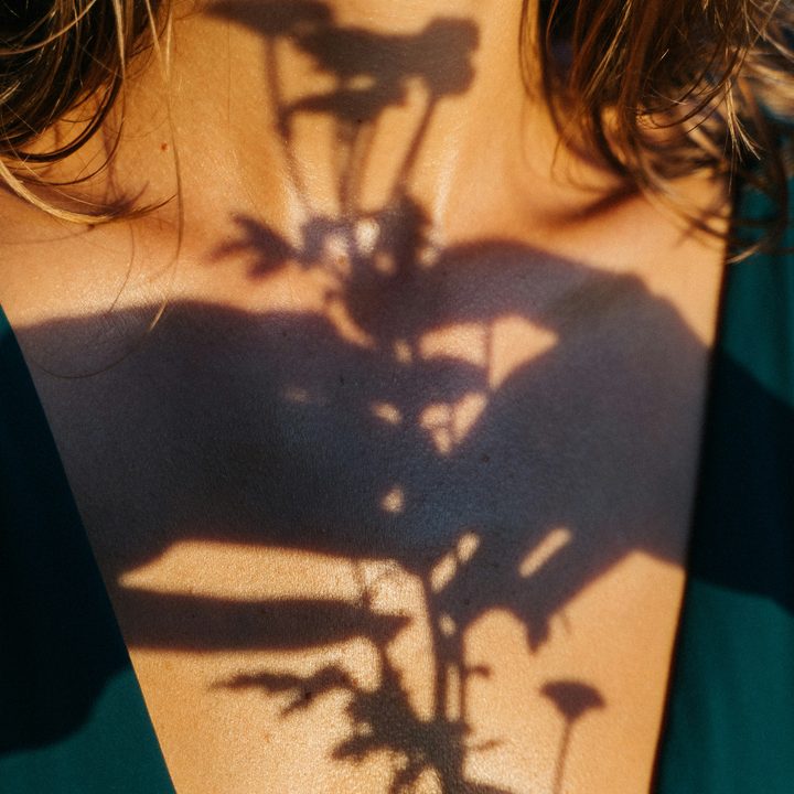 Sunlight casting a flower's shadow across bare shoulders