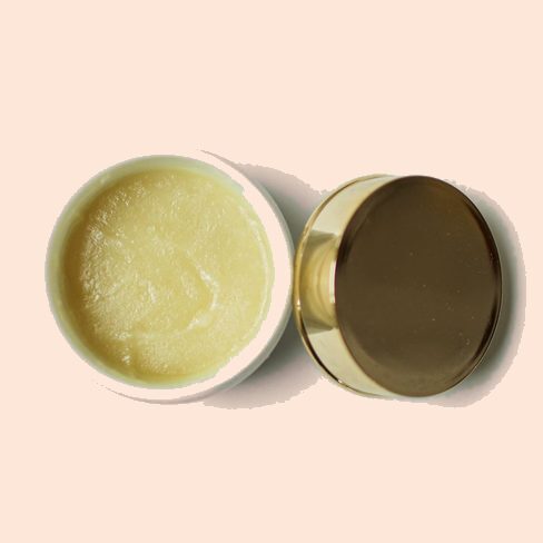 An open jar of whipped body butter beside its gold lid