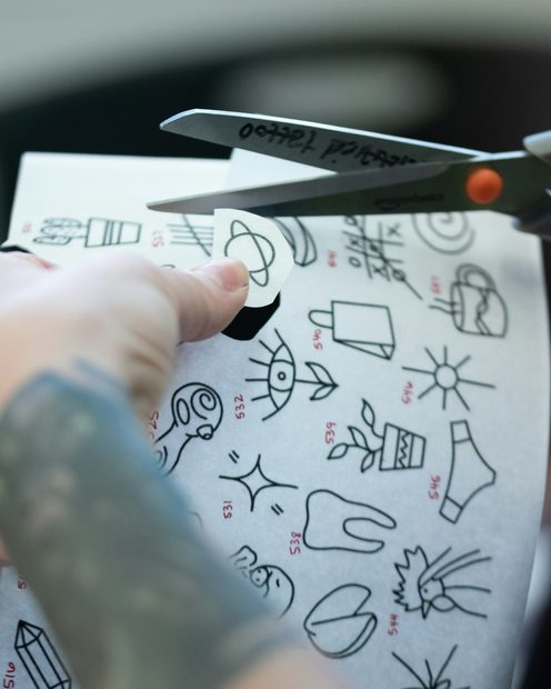 Scissors cutting out a sheet of small flash designs