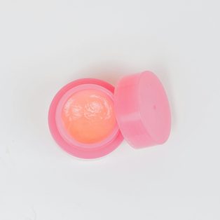 A small pink pot of lip balm with its lid off