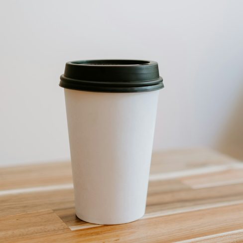 A takeaway coffee cup on a wooden cafe table