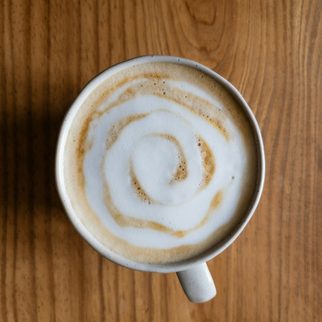 A latte with a spiral of foam on a wooden table