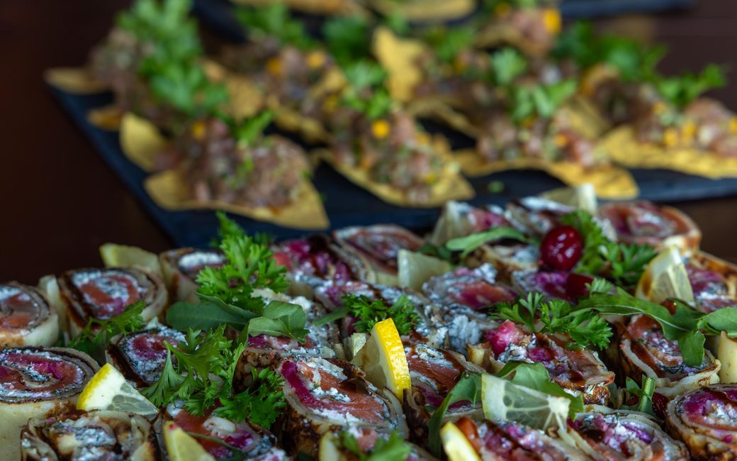 Rolled canapés with herbs laid out on a slate platter