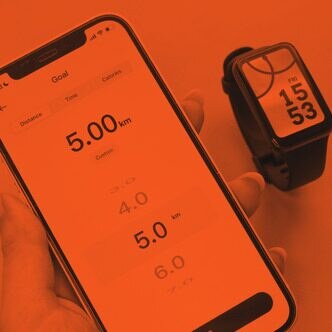 Hand holding a phone with a workout timer beside a fitness watch