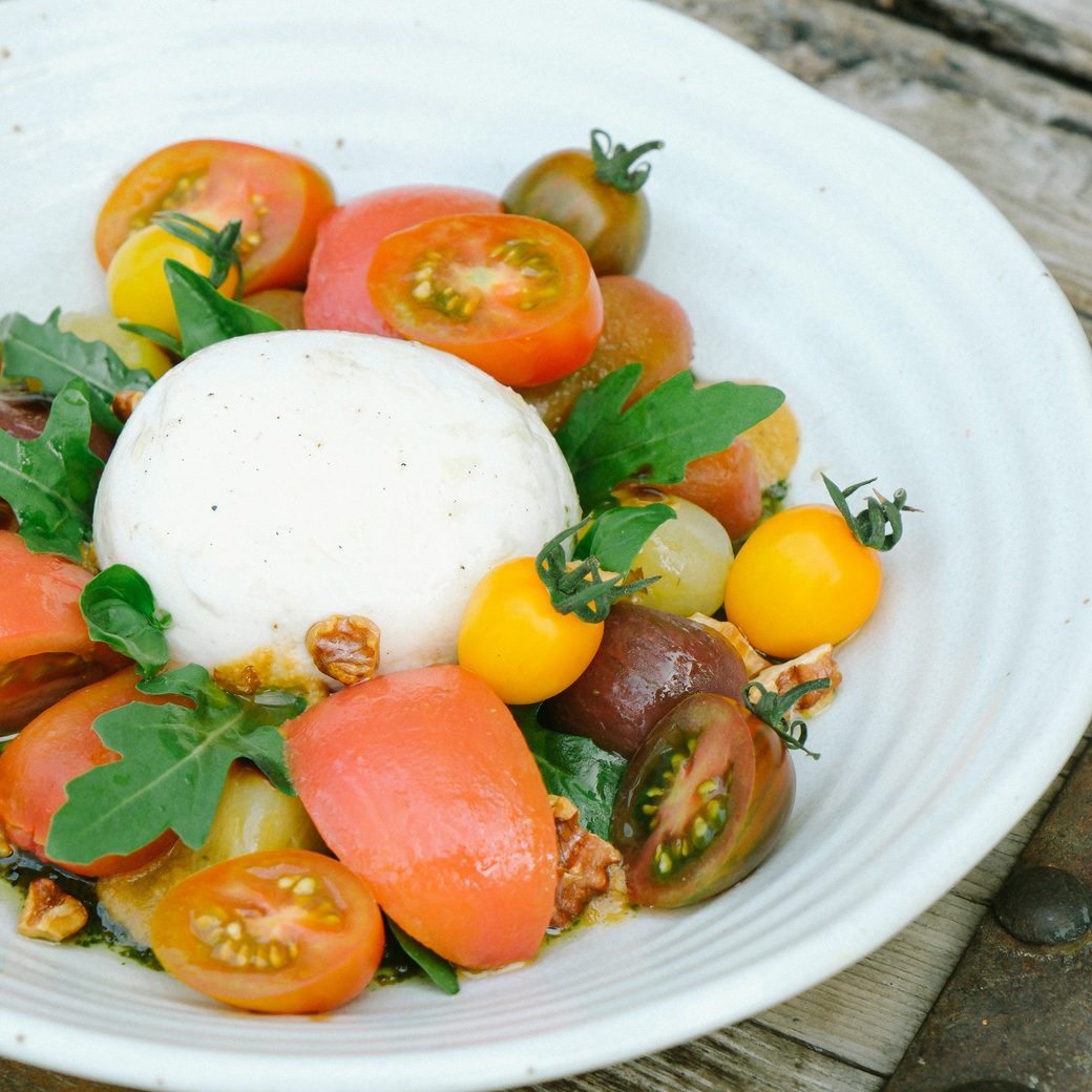 Heirloom tomatoes and burrata with basil in a white bowl