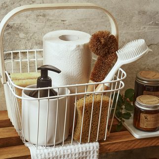 A wire basket of cleaning brushes and supplies