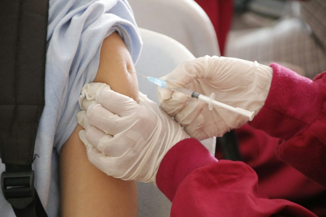 Gloved hands giving a flu shot in an upper arm
