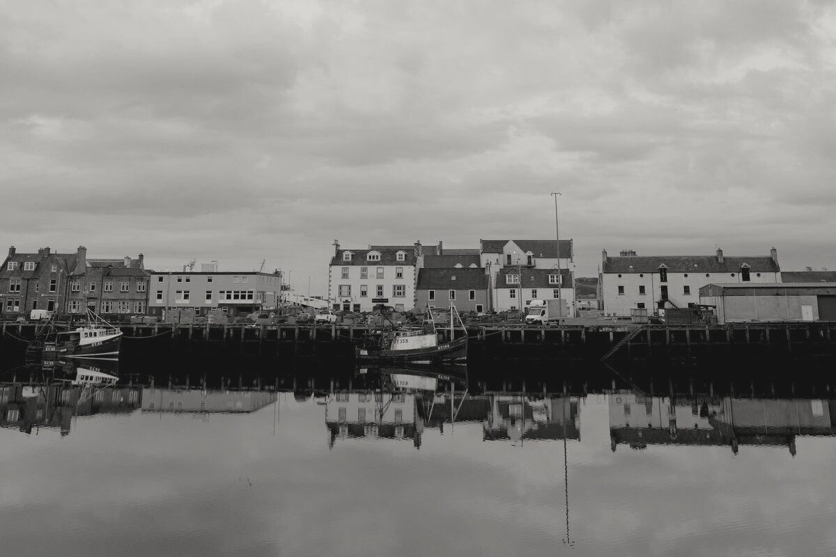 Houses and boats reflected in a still harbor