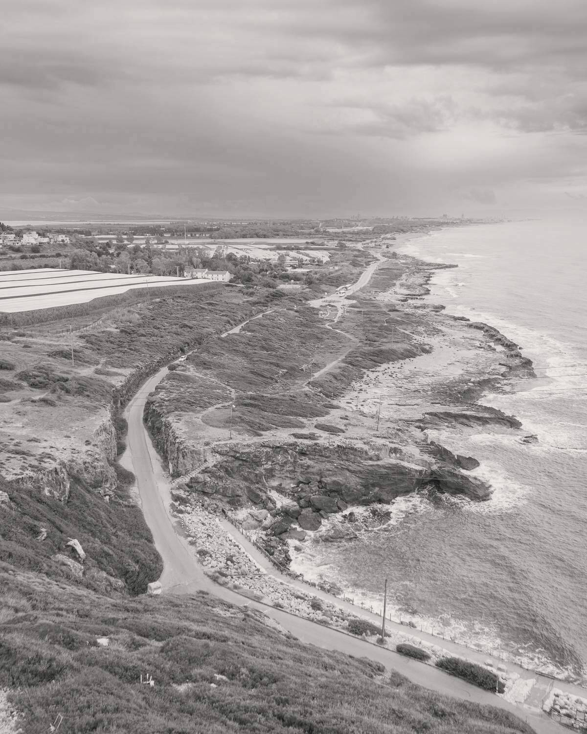A road winding along a rocky coastline under a gray sky
