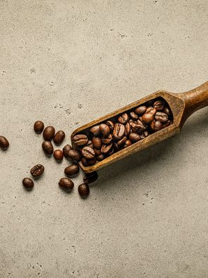 A wooden scoop of coffee beans on stone