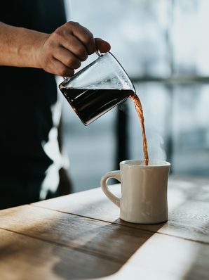 Coffee being poured from a glass carafe into a mug