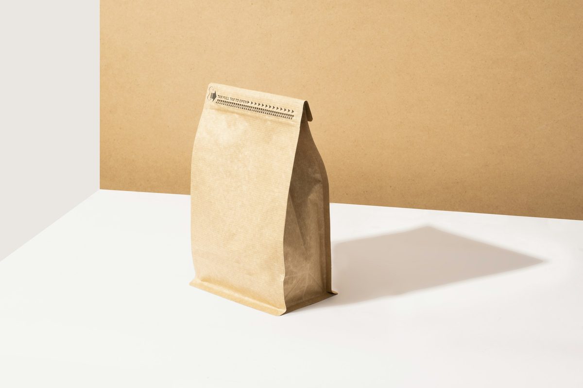 A plain kraft paper coffee bag standing on a white table