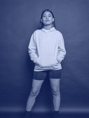 Woman in a pale cropped hoodie and black shorts