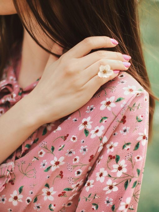Close-up of a hand with a flower ring on a pink floral dress