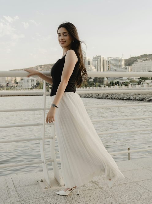 A woman in a flowing white pleated skirt by the sea