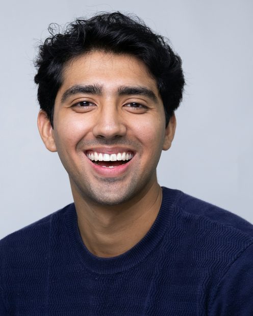 Marcus Nwosu laughing in a navy sweater