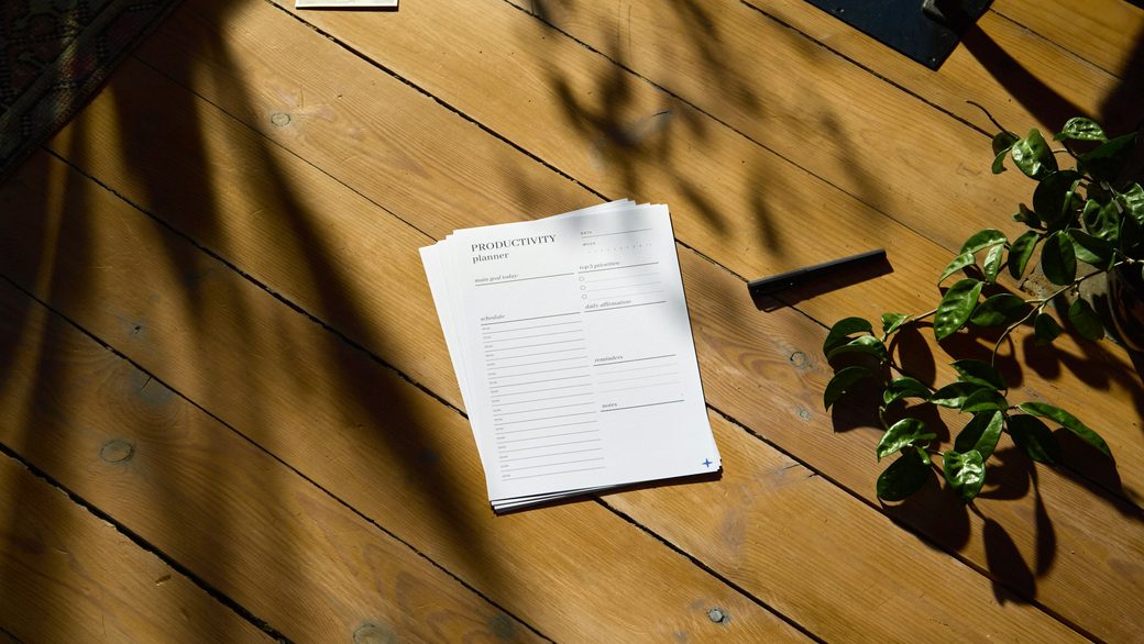 A planning sheet on a sunlit wooden desk beside a plant