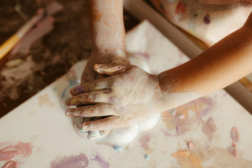 A child's paint-covered hands pressing onto paper
