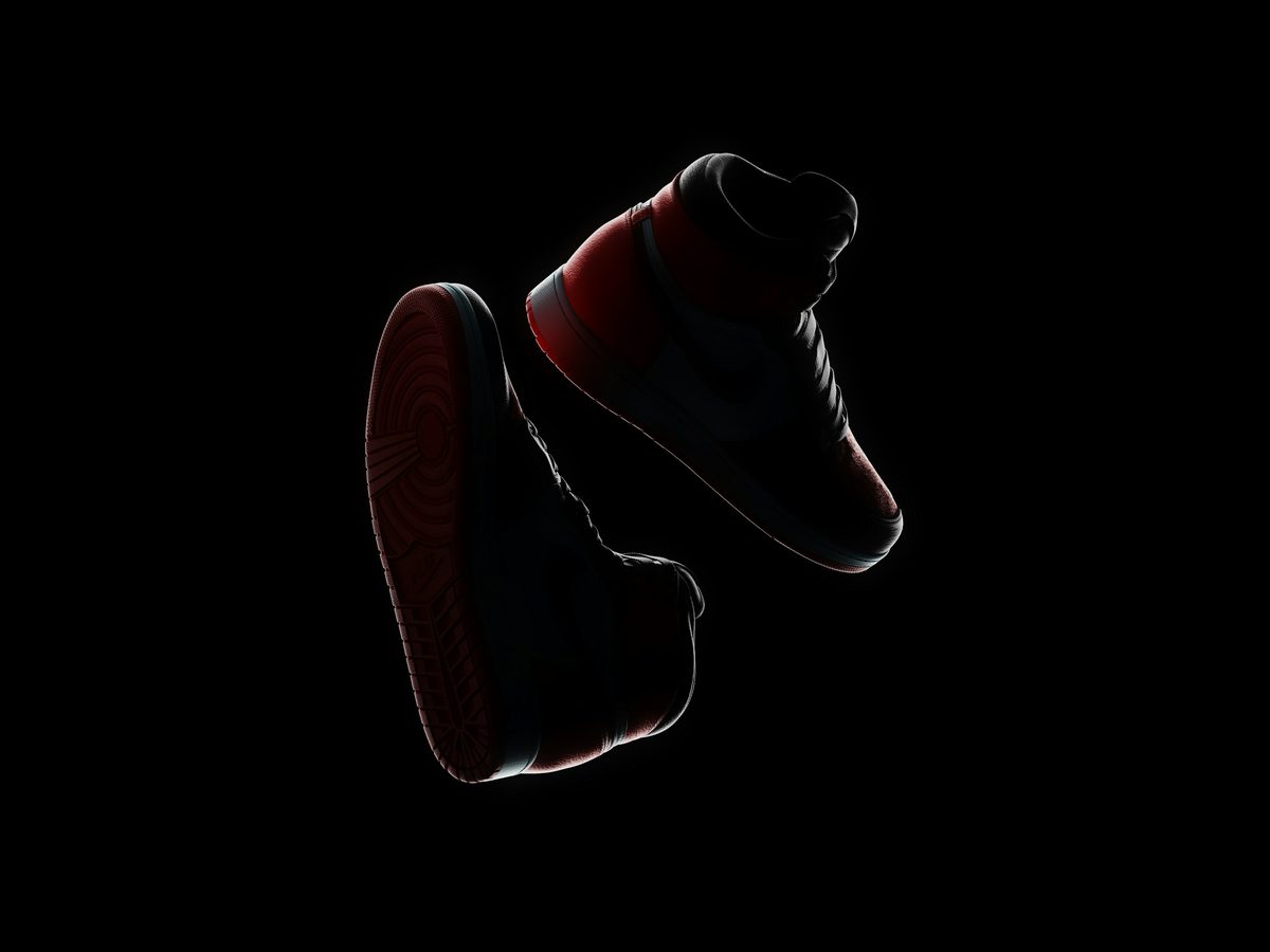 A single high-top sneaker rim-lit in red against total darkness
