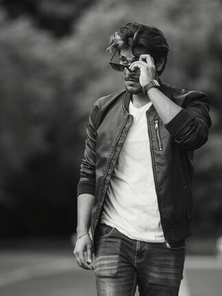 A model in a black leather jacket and white tee walking down a road