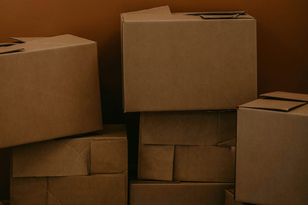 Plain cardboard boxes stacked against a warm brown wall
