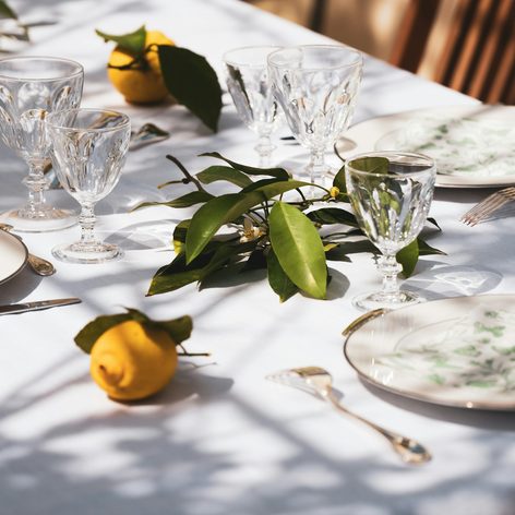 A table laid with a pale cloth, patterned plates and lemons