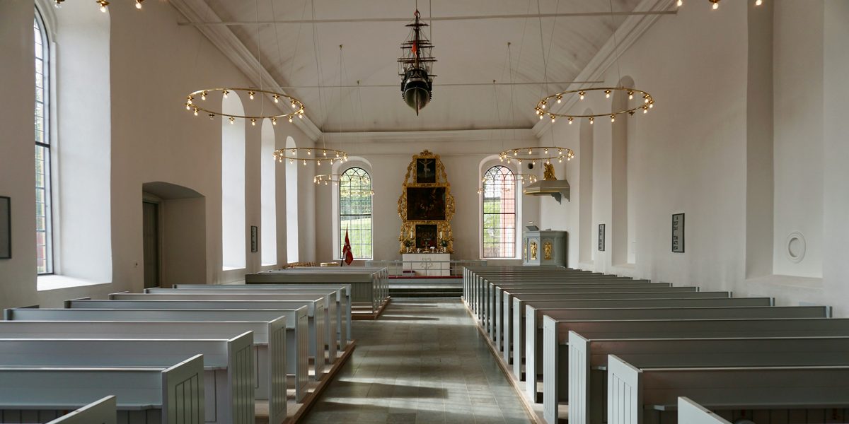 A bright church sanctuary with pale gray pews leading to the altar