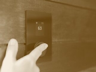 A hand turning a dial on a wall panel