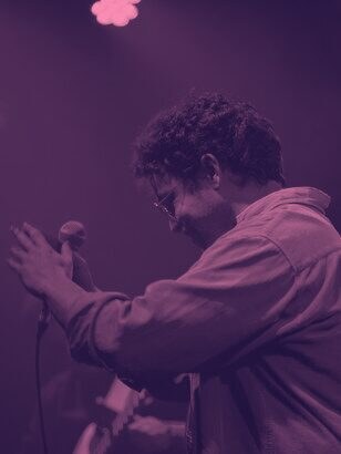 A singer at the mic under colored stage lights