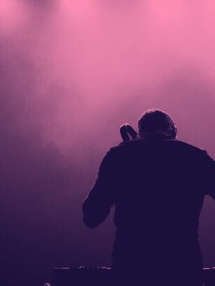 A DJ silhouetted in haze and spotlight