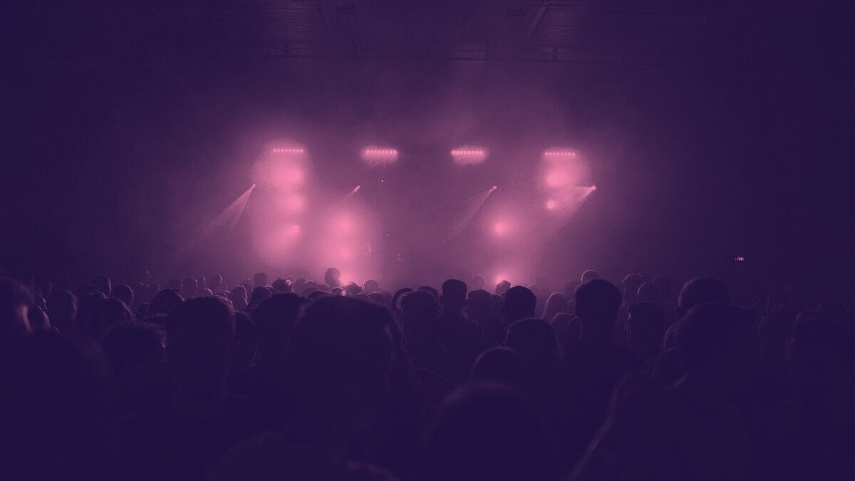 A crowd with raised hands in front of a lit stage