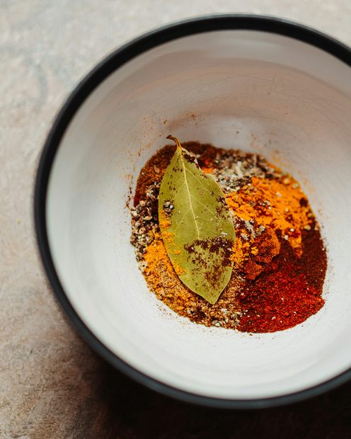 Smoked paprika in a white bowl with a bay leaf