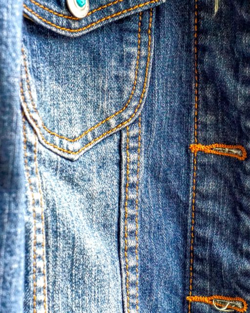 Close-up of a cropped denim jacket with copper buttons
