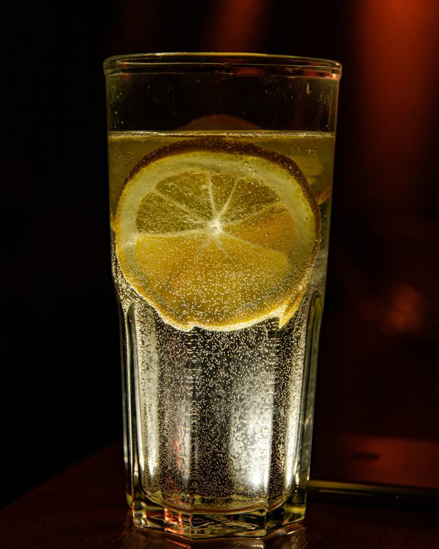 A glass of sparkling citrus soda with a lemon slice, bubbles rising