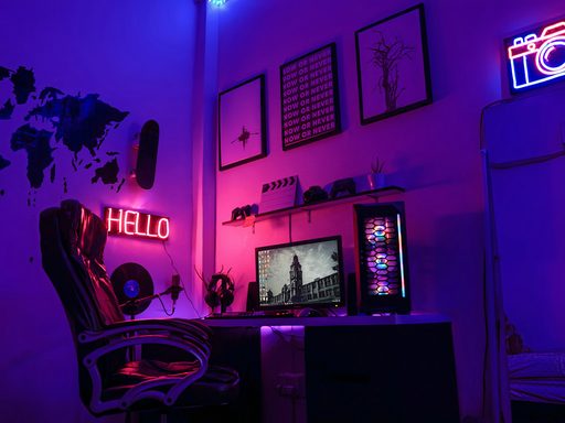 Gaming desk glowing purple and pink in a dark room
