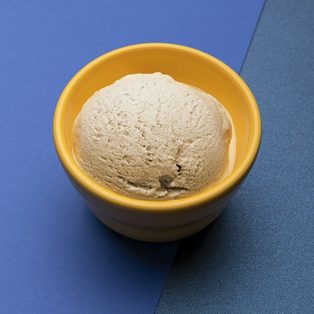 A scoop of fior di latte gelato in a yellow bowl on a blue table