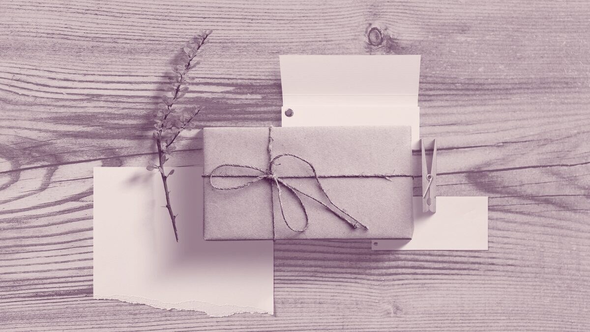 A small present wrapped in brown paper and twine beside a blank card