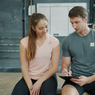A trainer and a client reviewing a plan on a clipboard