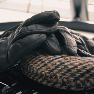 Dark leather gloves resting on a houndstooth wool cap