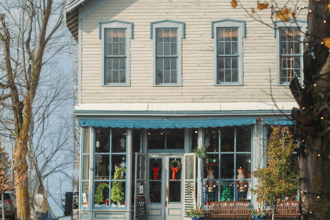 A white clapboard shopfront with a blue awning on a winter street