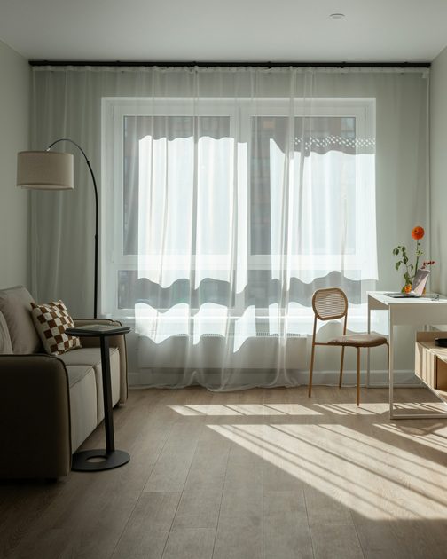A bright living room with sheer curtains and sun on the floor