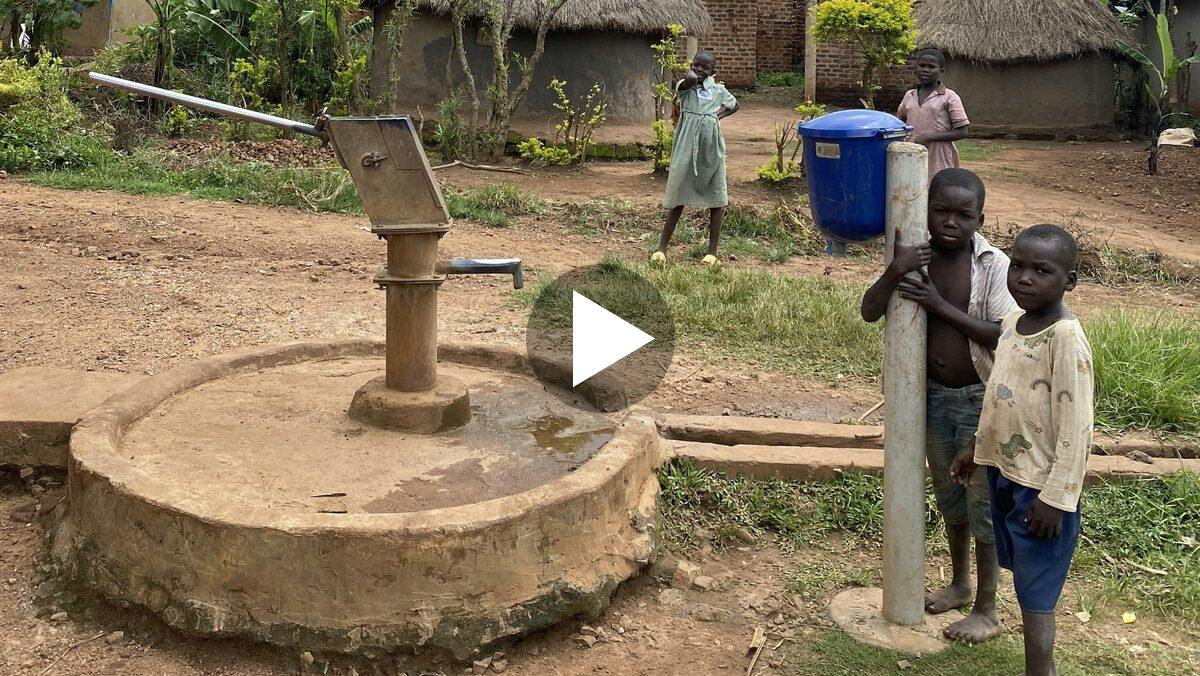 Play the film: children standing by a new water pump in their village